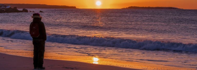 person watching the sunset over a wavy lake