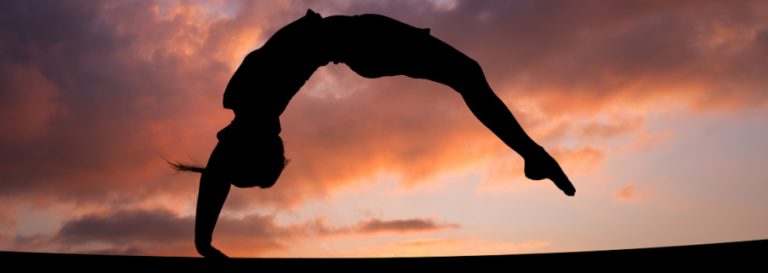 silhouette of someone doin a back hand spring with sunset in background