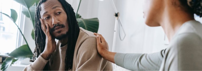A man being comforted with his friend's hand on his shoulder