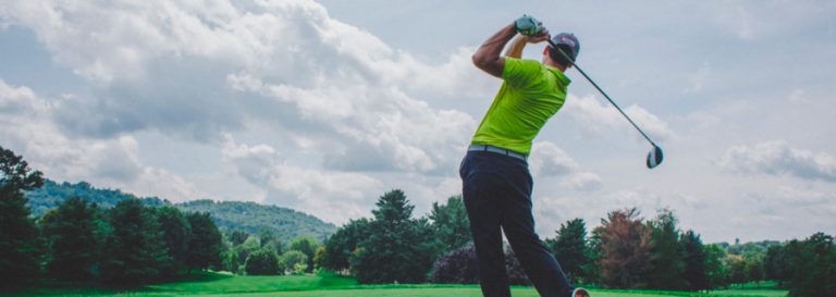 Golfer drives a ball off a tee
