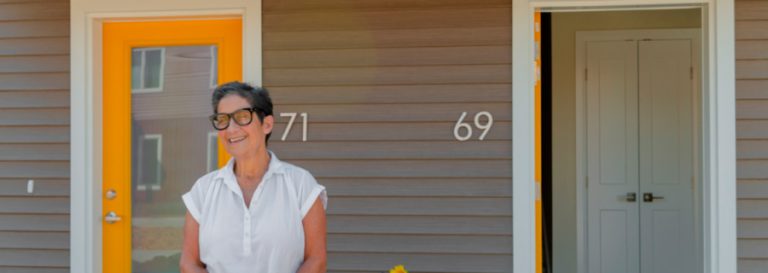 A woman stands on the porch of a house