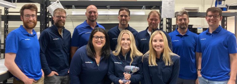 Team of staff smiling and holding a tool