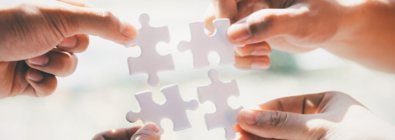 4 hands holding puzzle pieces together