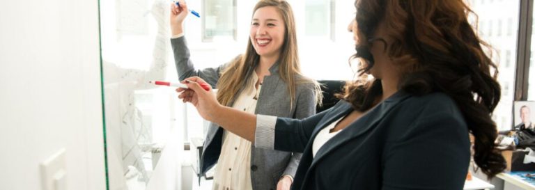 Woman smiling and writing on whiteboard